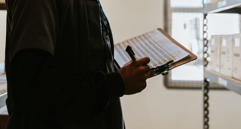 Industrial worker managing inventory with a clipboard and checklist, representing a quality control process