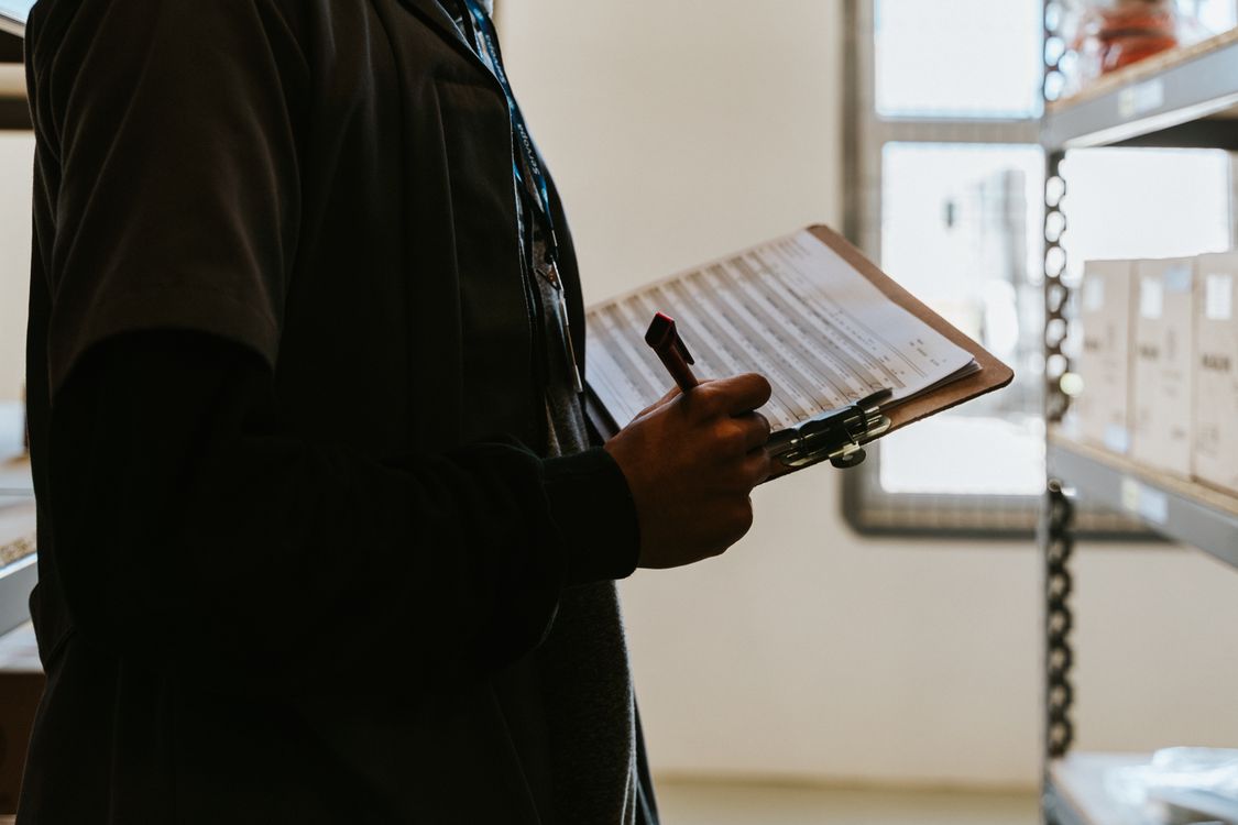 Industrial worker managing inventory with a clipboard and checklist, representing a quality control process