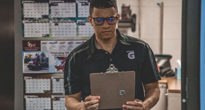 Warehouse worker checking documents on a clipboard, representing a documented standard operating procedure