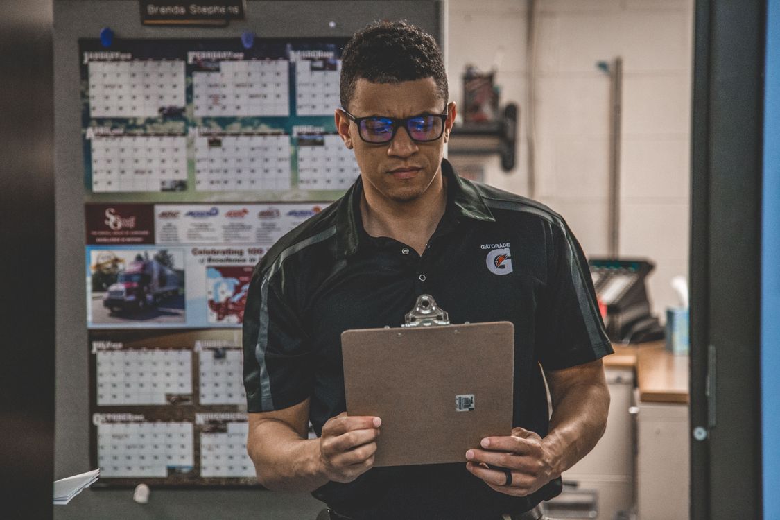 Warehouse worker checking documents on a clipboard, representing a documented standard operating procedure