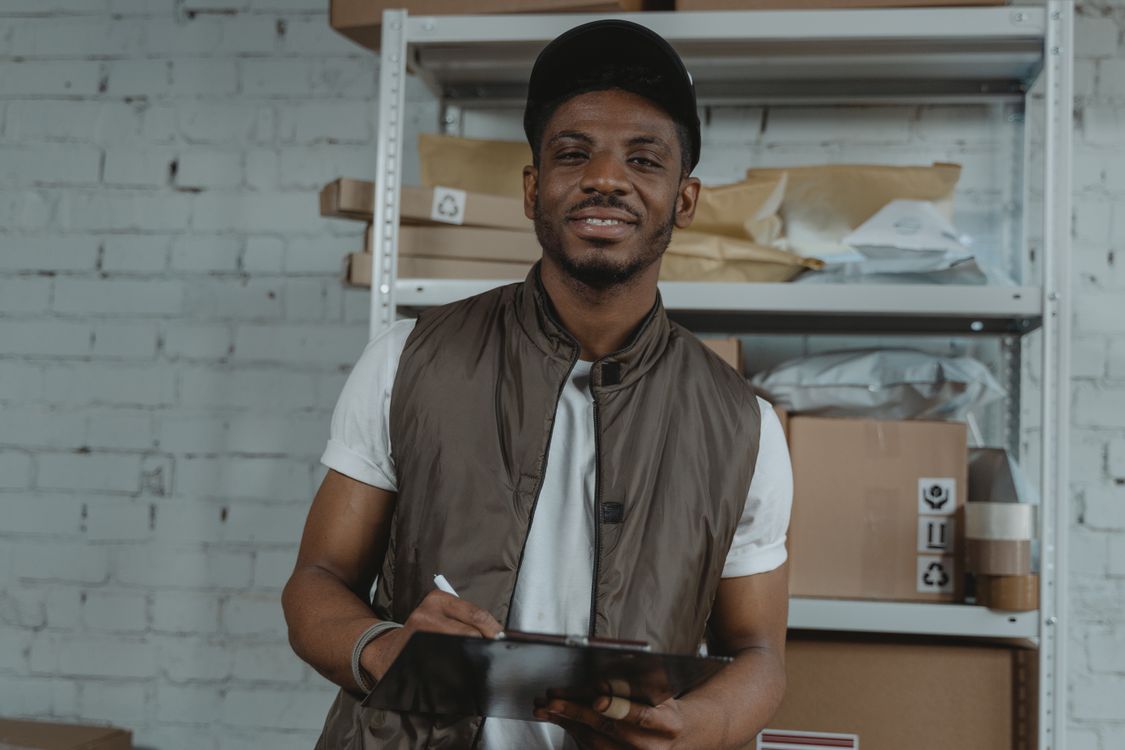 Warehouse employee holding a clipboard surrounded by packages, representing a weekly operations review