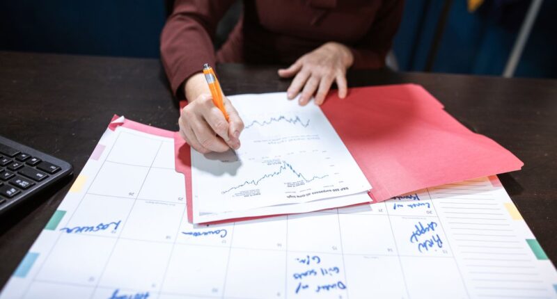 Person reviewing a financial document on an organized desk, representing vendor management for a small business