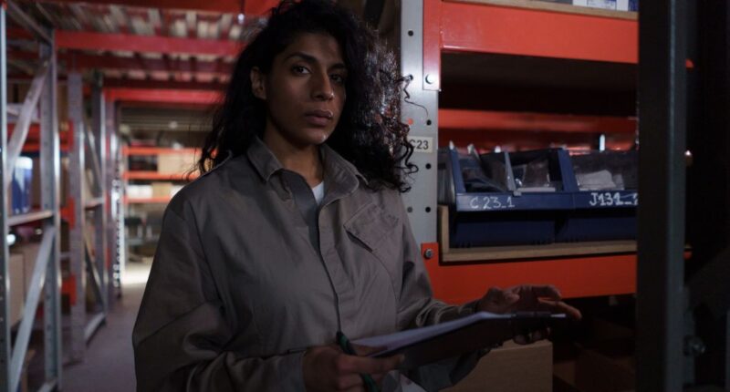 Warehouse worker in uniform holding a clipboard for stock management, representing scaling business operations