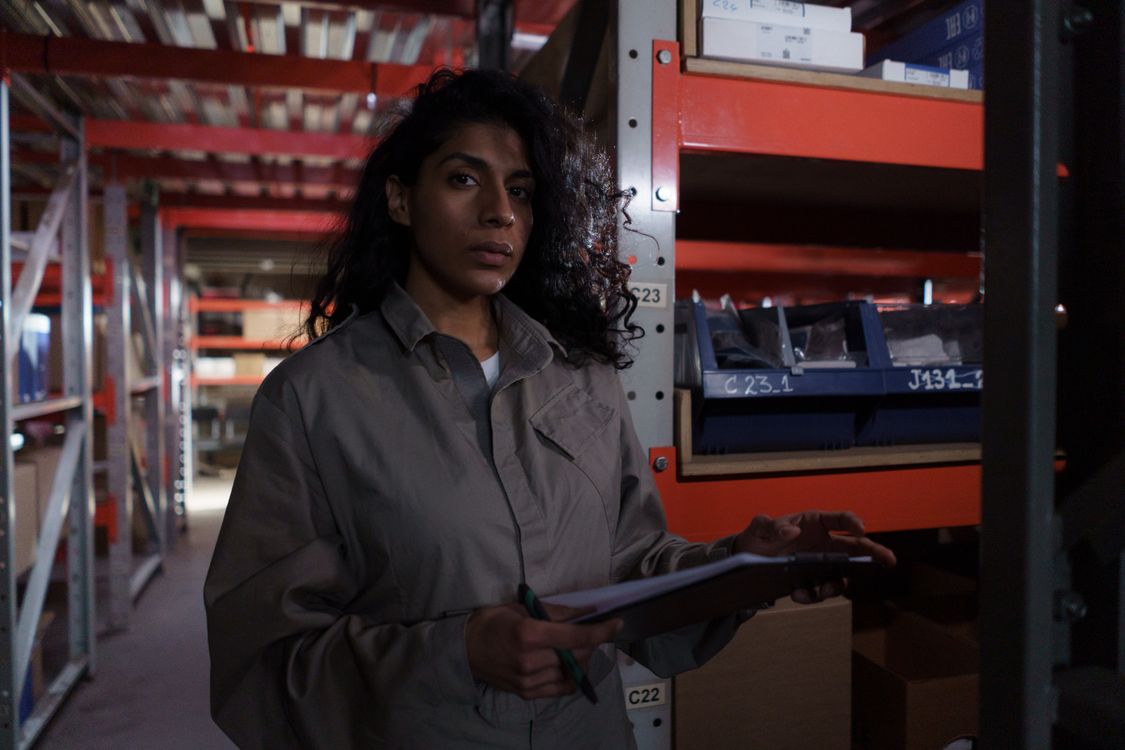 Warehouse worker in uniform holding a clipboard for stock management, representing scaling business operations