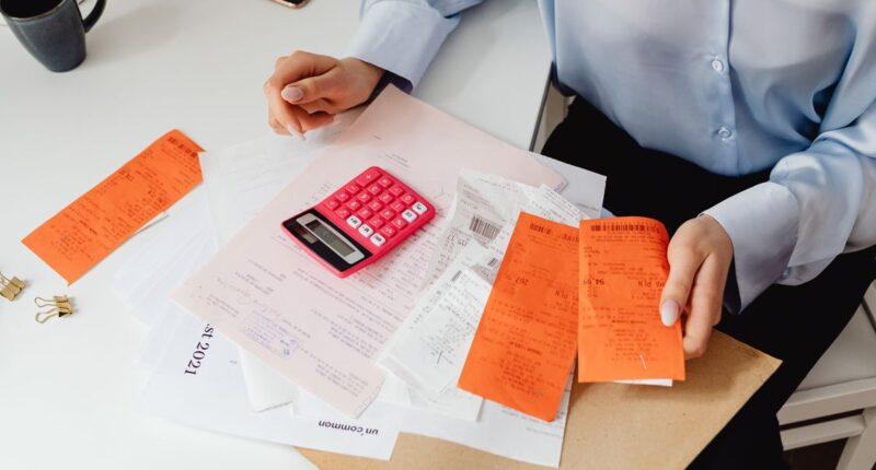 Woman reviewing receipts and calculating expenses manually with a calculator, representing an outdated business process