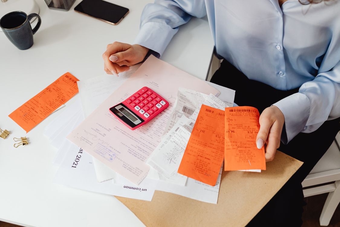 Woman reviewing receipts and calculating expenses manually with a calculator, representing an outdated business process