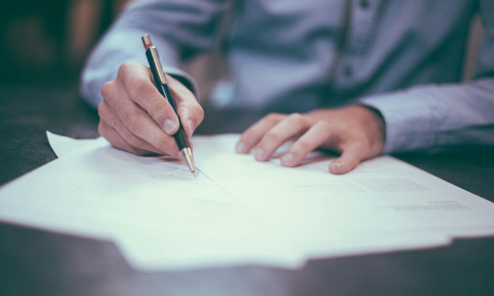 Person reviewing and writing on a document, representing reading and negotiating a job offer