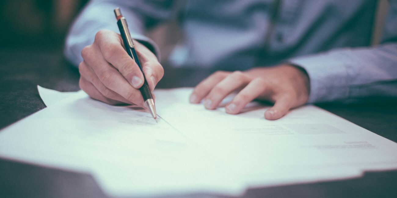 Person reviewing and writing on a document, representing reading and negotiating a job offer