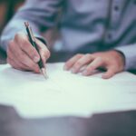 Person reviewing and writing on a document, representing reading and negotiating a job offer