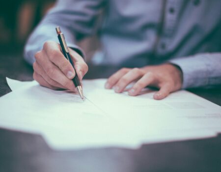 Person reviewing and writing on a document, representing reading and negotiating a job offer
