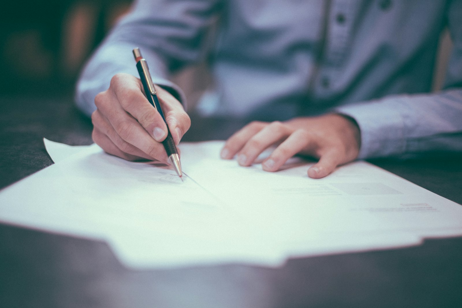 Person reviewing and writing on a document, representing reading and negotiating a job offer