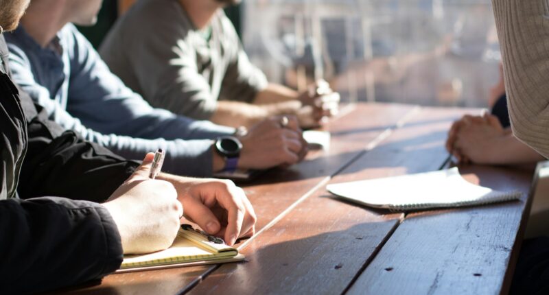 Team sitting together at a table working, representing delegation within a small team