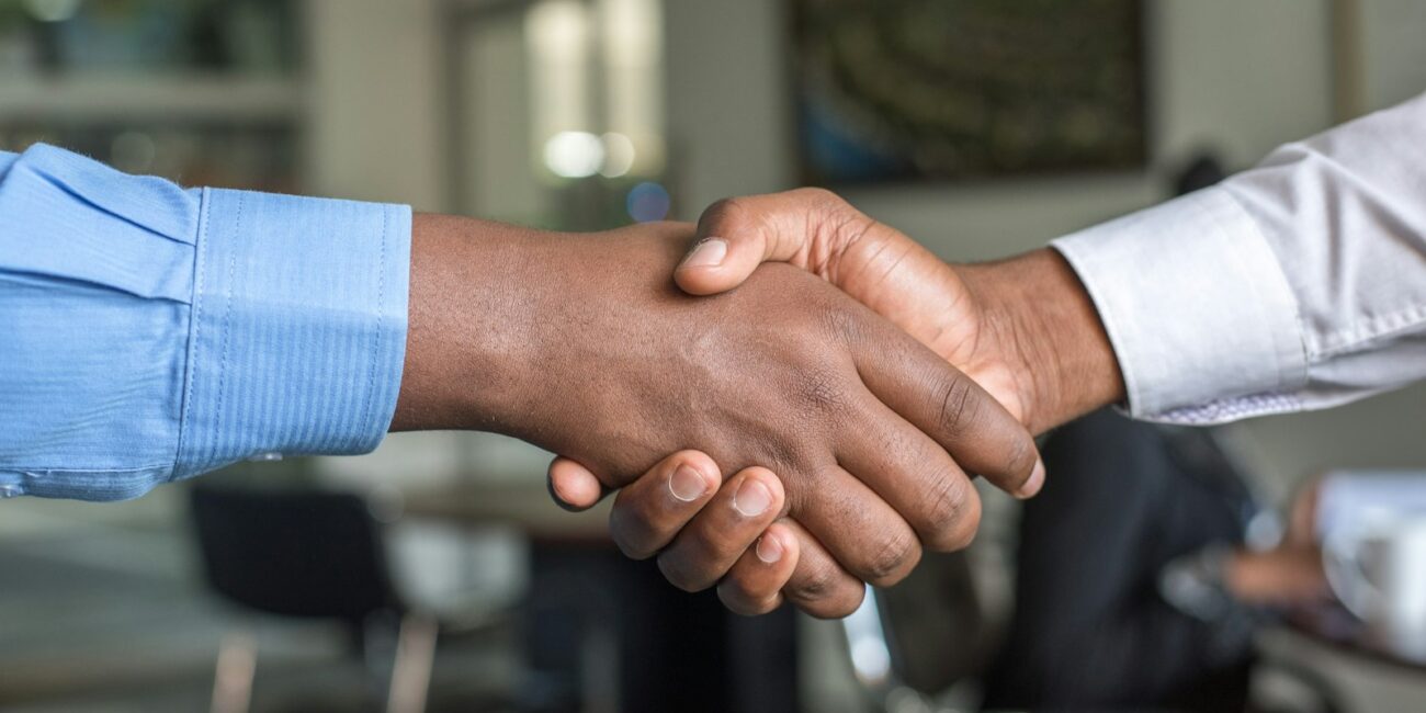 Two people shaking hands over a deal, representing the choice between equity and salary