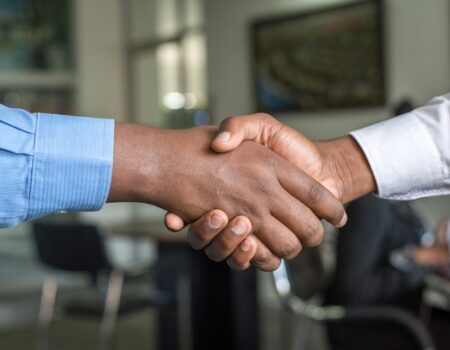 Two people shaking hands over a deal, representing the choice between equity and salary