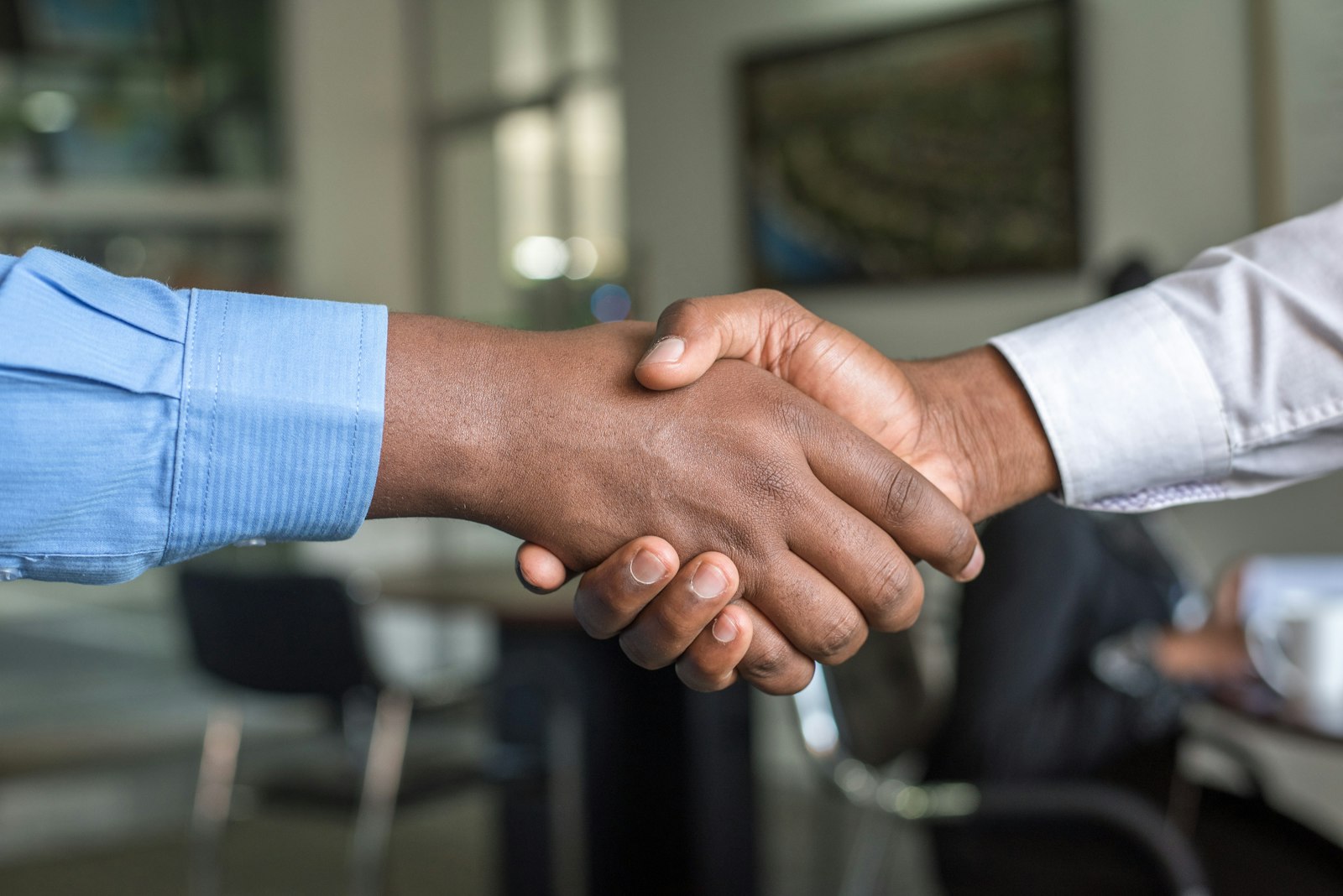 Two people shaking hands over a deal, representing the choice between equity and salary