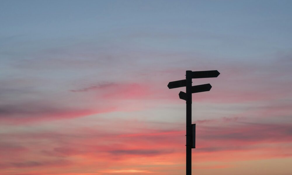 Silhouette of a road sign at a crossroads during golden hour, symbolizing a major career decision