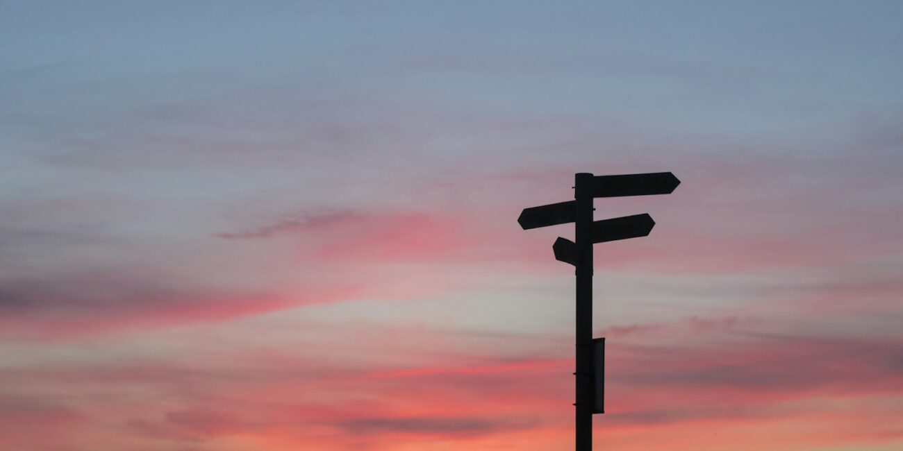 Silhouette of a road sign at a crossroads during golden hour, symbolizing a major career decision