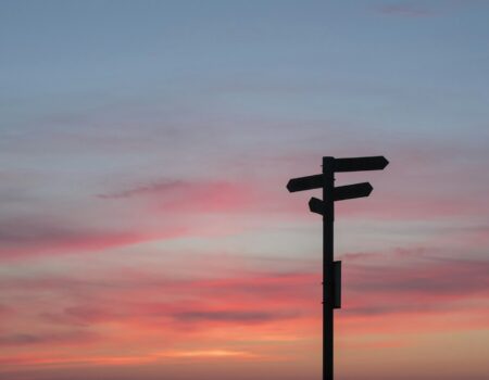 Silhouette of a road sign at a crossroads during golden hour, symbolizing a major career decision