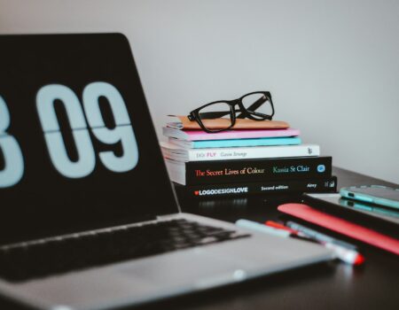 A laptop and books on a desk, representing crafting a standout resume and portfolio