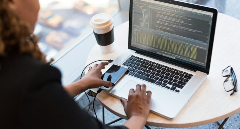 Woman working on a MacBook in an office setting, representing an interview conversation