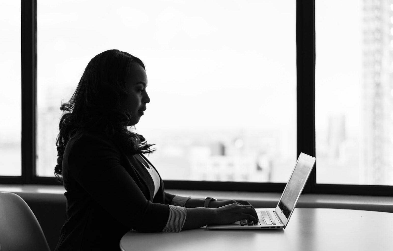 Woman writing on a laptop, representing drafting a job post