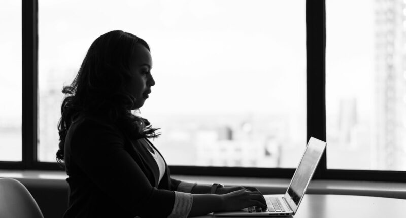 Woman writing on a laptop, representing drafting a job post