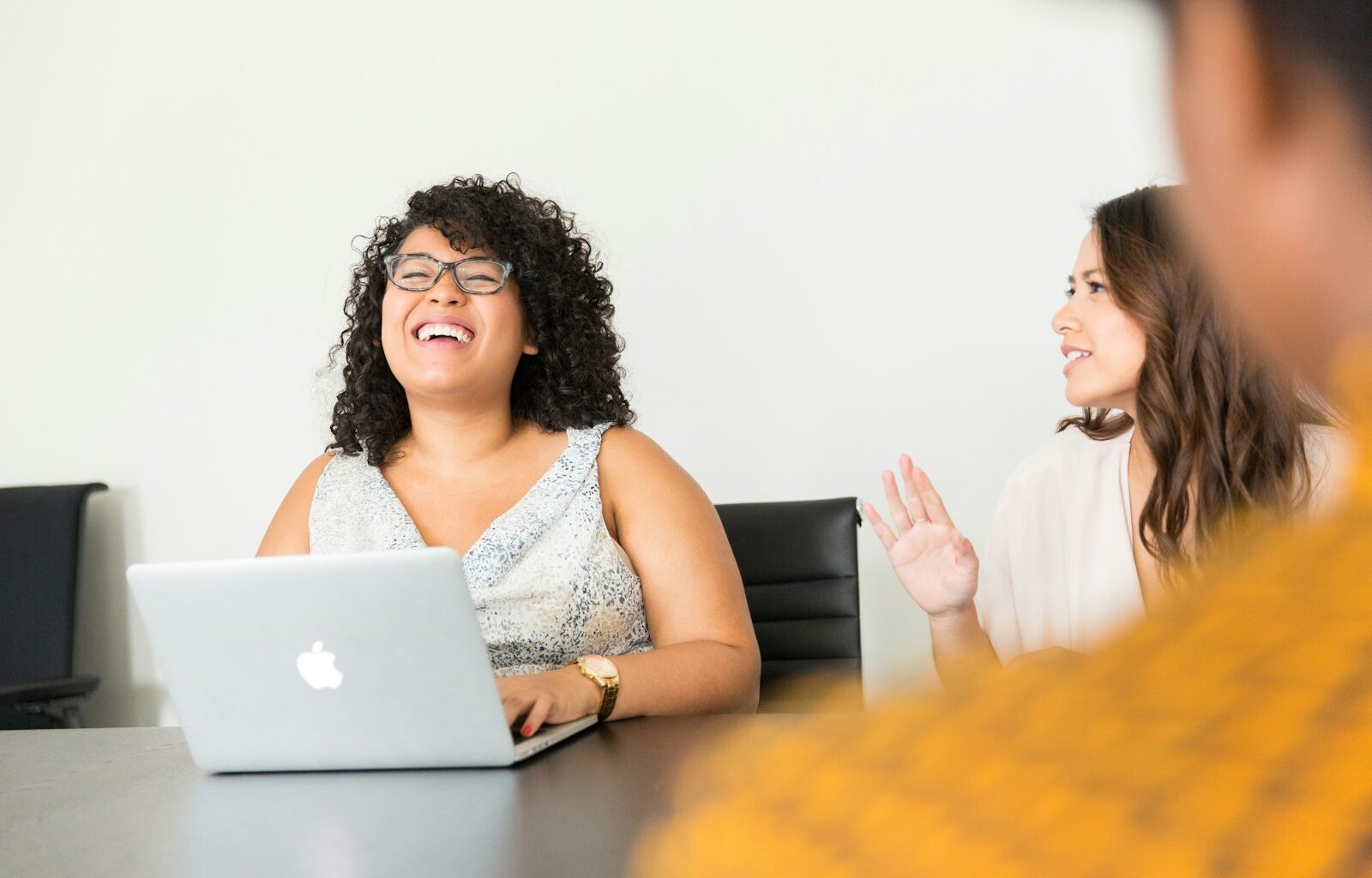 Woman sitting in front of a laptop in a business setting, representing a one-on-one feedback conversation