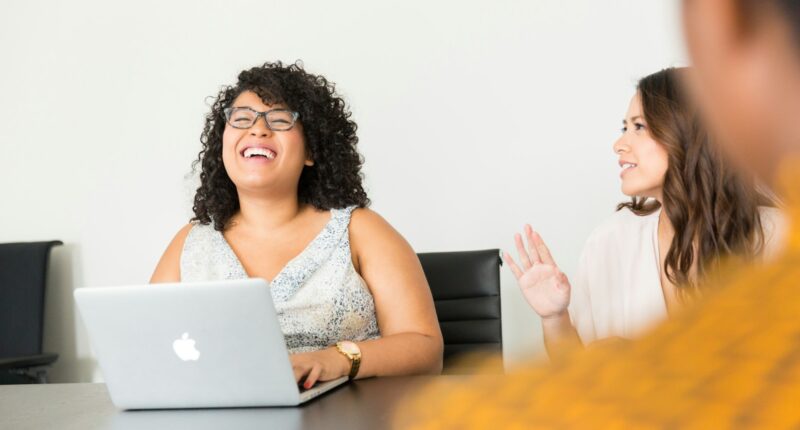 Woman sitting in front of a laptop in a business setting, representing a one-on-one feedback conversation