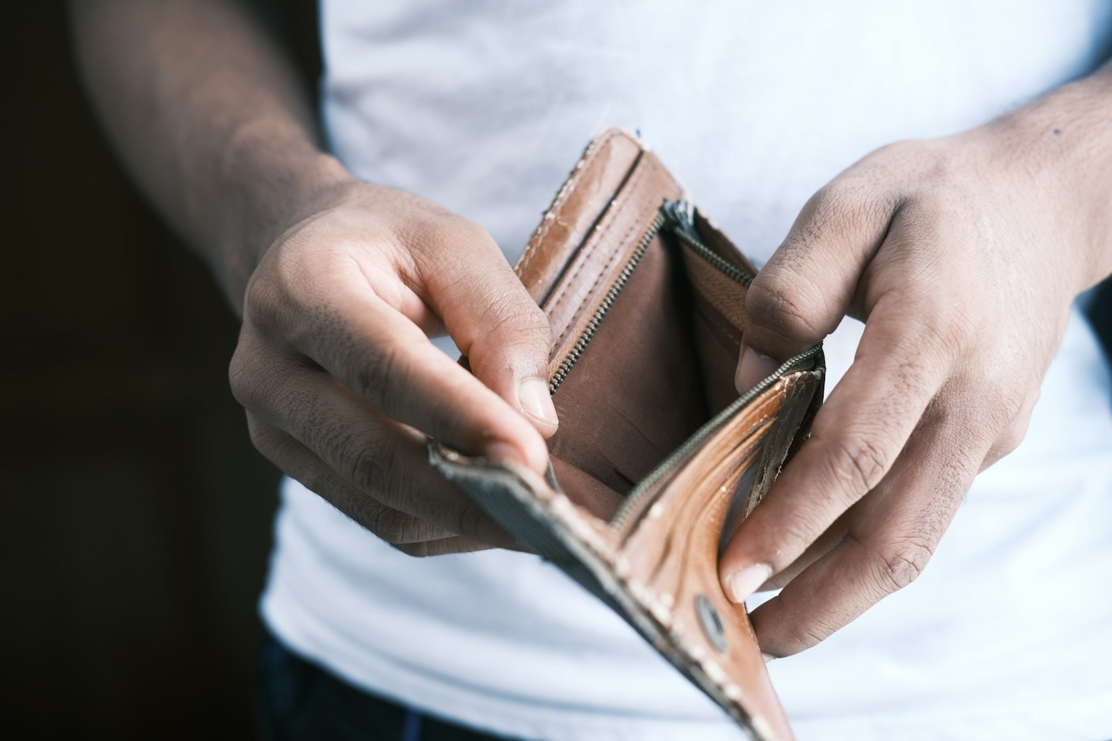 A person holding an open leather wallet, representing the cash flow gap that can quietly sink a profitable business