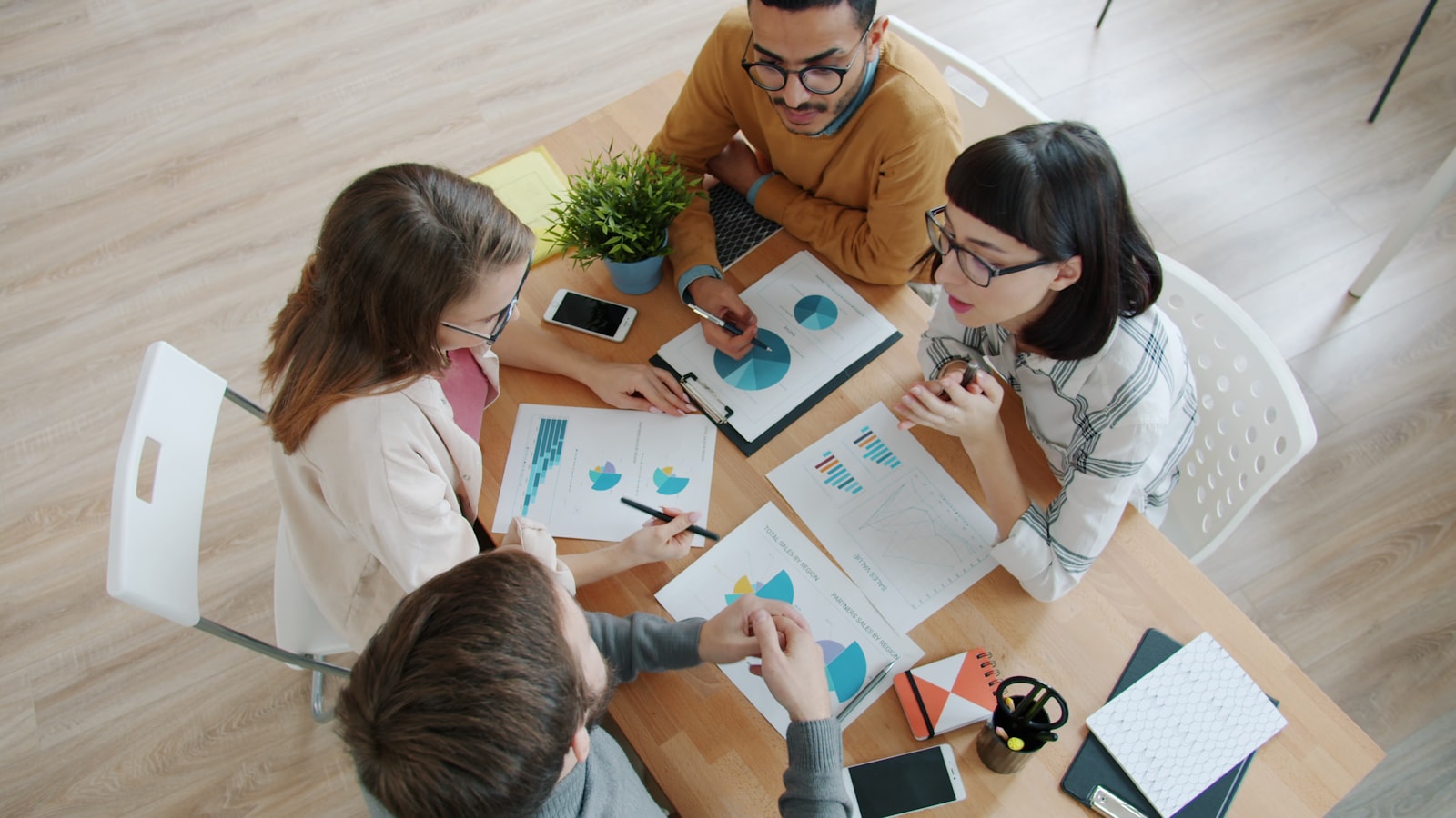 Four people collaborating around a table with documents, representing studying a competitor's playbook